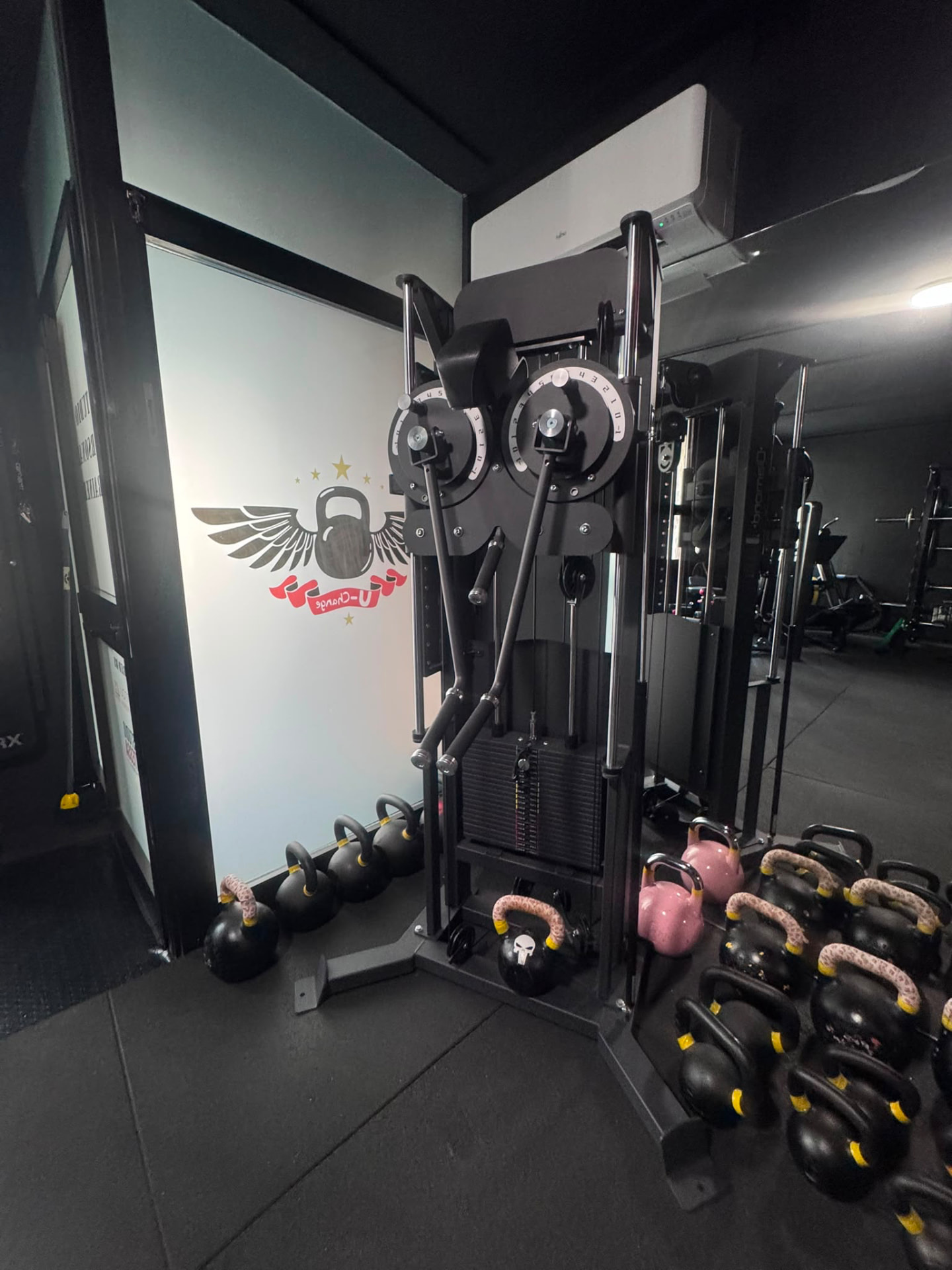Zona kettlebell e cross cable con il logo U-Change sulla parete